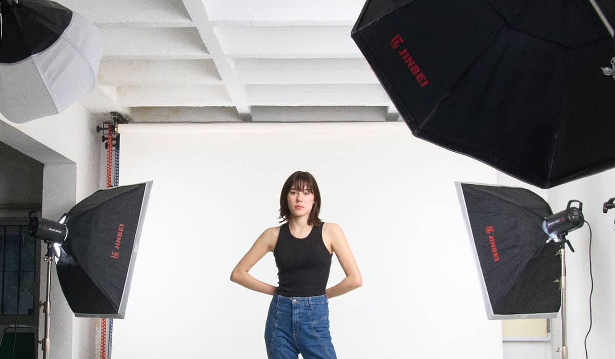 Modelo en estudio con iluminación y fondo blanco para sesión fotográfica.
