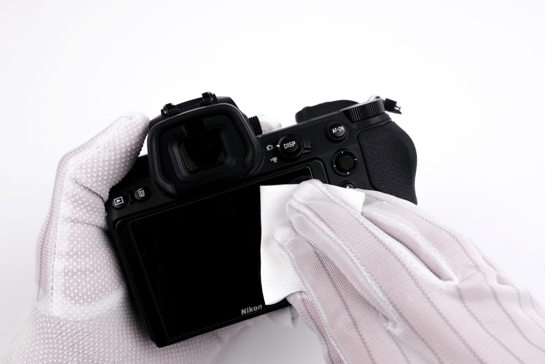Persona limpiando una cámara Nikon con paño de microfibra.