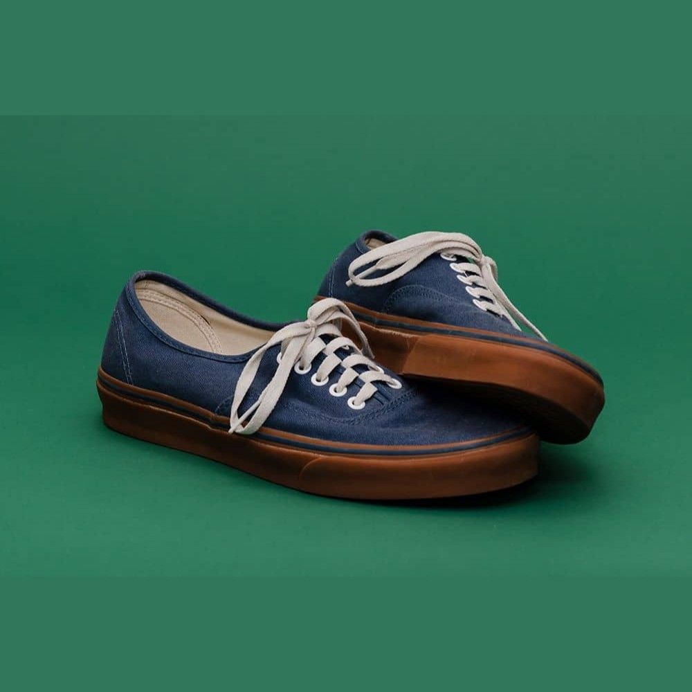 Ejemplo de foto con fondo de papel sinfín verde (Deep): zapatillas casuales azul marino con suela de goma marrón y cordones blancos
