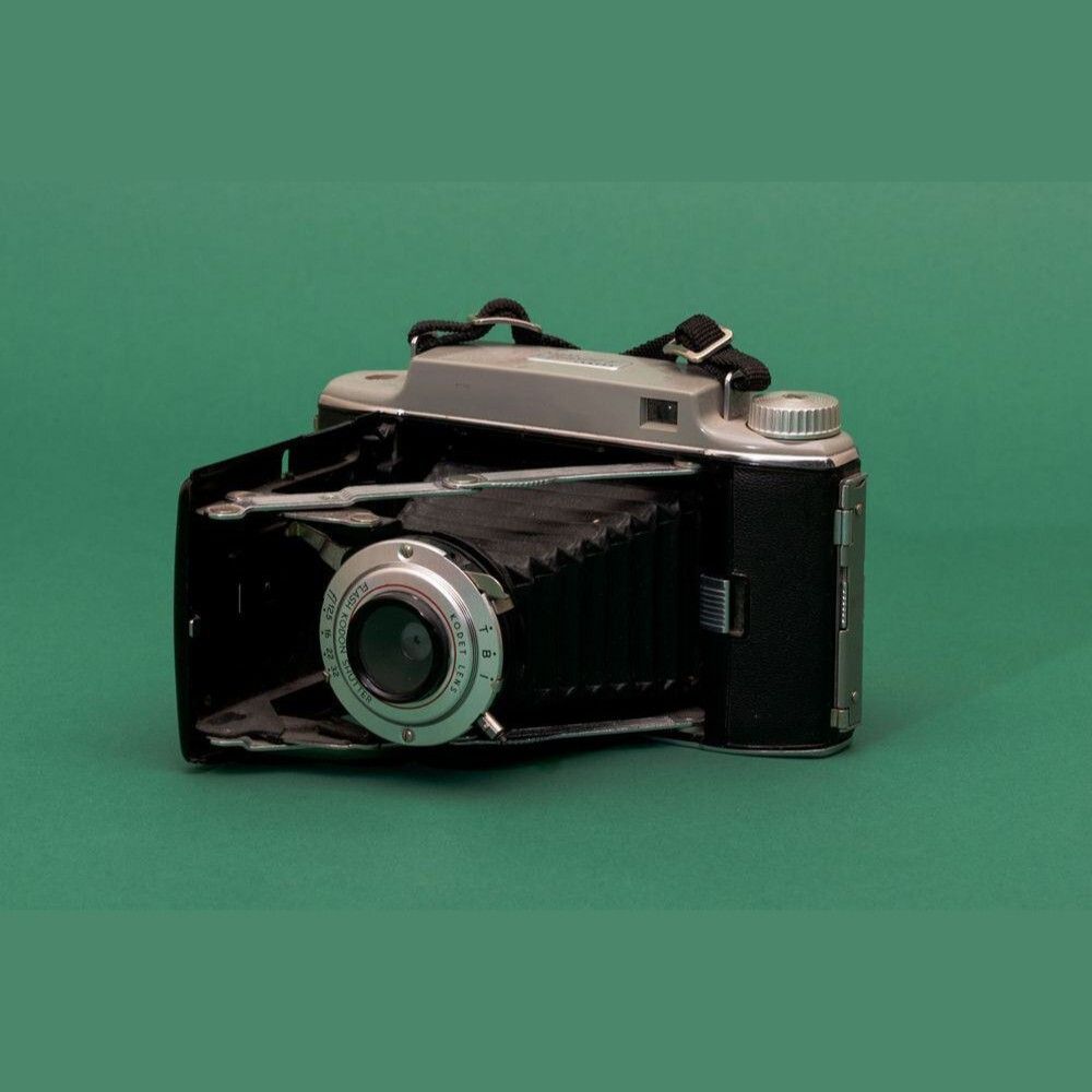 Cámara antigua de película en fondo verde para fotografía y colección.